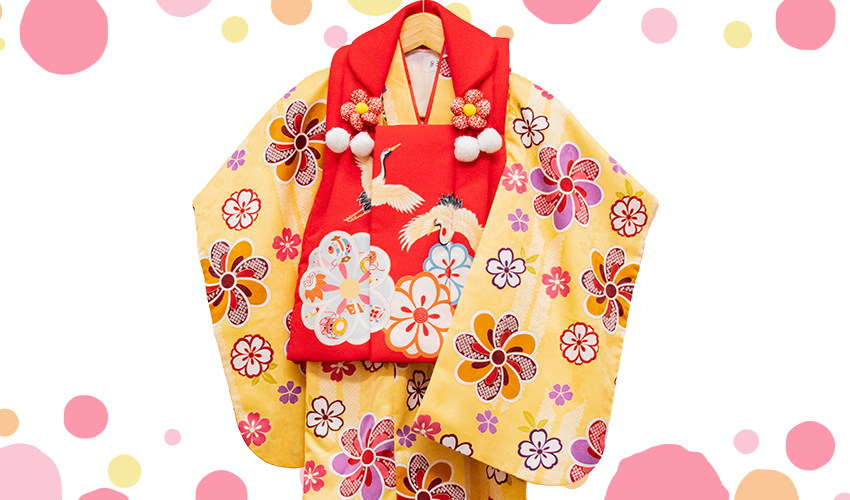 七五三女児3歳被布コレクション5。カラシ地の古典柄の着物に赤地の鶴柄の被布です